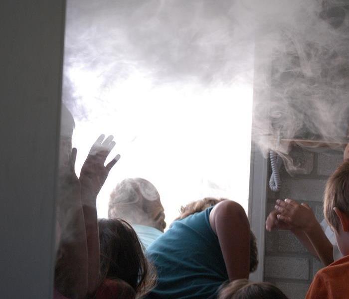 in this picture you will see children following fire safty practice when a room is filled with smoke. 