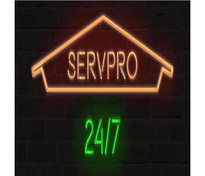 a neon sign against a black background that reads " SERVPRO 24/7"